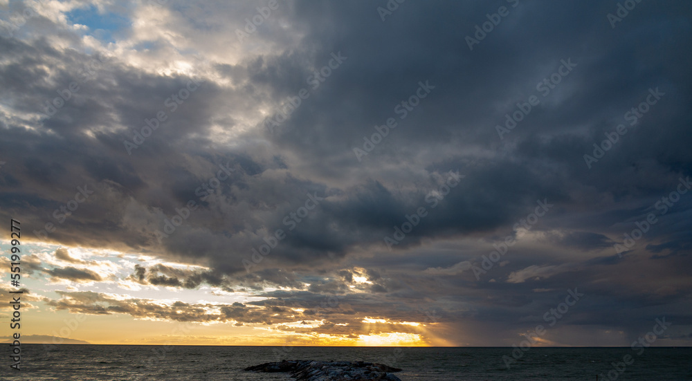 Sunset on the Mediterranean sea in front of Marina di Cacina on an autumn evening with clearing clouds Sunset on the Mediterranean sea in front of Marina di Cacina on an autumn evening with clearing clouds