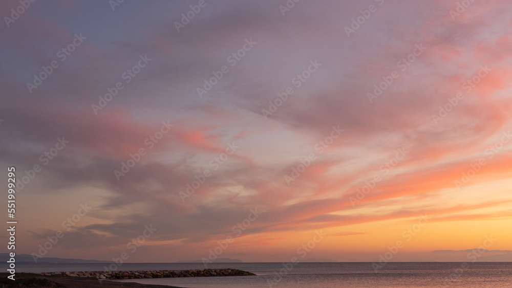 A red sunset over the Mediterranean sea in front of Marina di Cecina on an autumn evening with few clouds