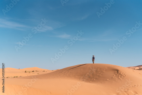 Fotografi lonely man in the middle of a dune in the desert