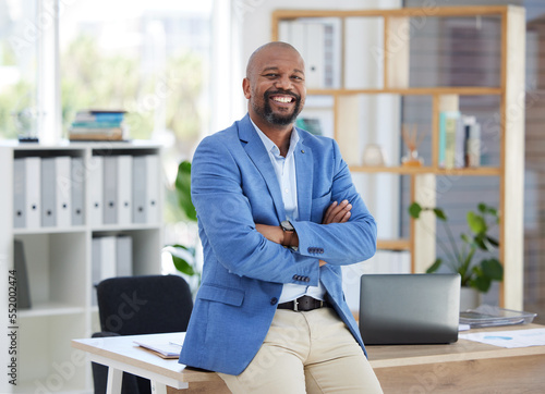 Success, corporate leadership and portrait of black man sitting on desk in modern office for startup. Management, marketing ceo and happy male entrepreneur with business vision in creative workplace photo