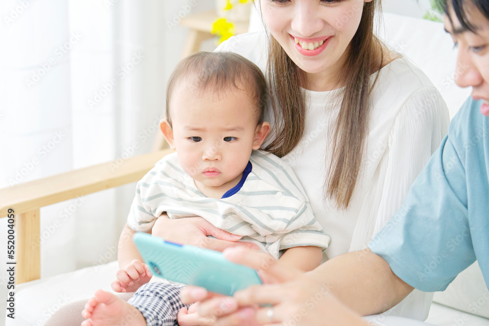 家で両親とスマホを見る赤ちゃん 家で両親とスマホを見る赤ちゃん