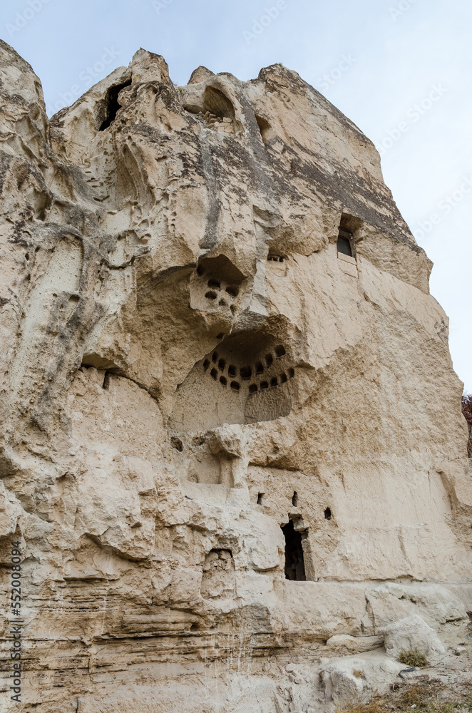 The vertical view of collapsing rock pillar with dovecote cave inside in Goreme city of Cappadocia region, Turkey