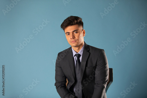 Portrait of a young business man looking at camera against blue background © IndiaPix