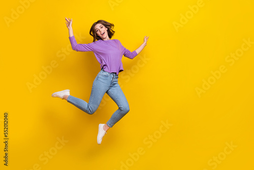 Full size portrait of overjoyed nice girl jumping have good mood empty space isolated on yellow color background © deagreez