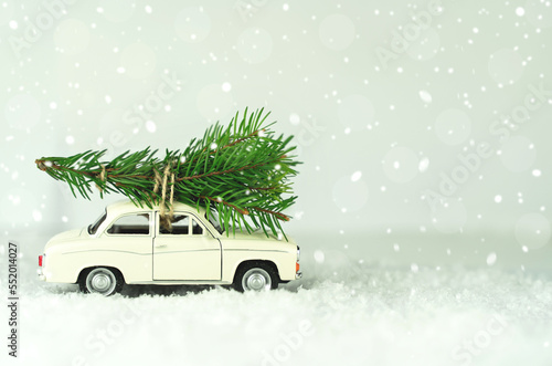 White car with christmas tree on snowy winter background. Merry Christmas and Happy New Year concept
