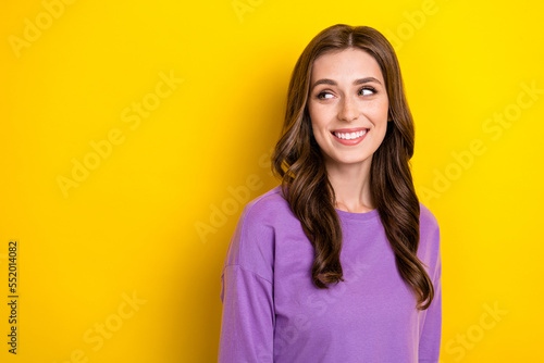 Portrait of cheerful adorable girl beaming smile look interested empty space isolated on yellow color background