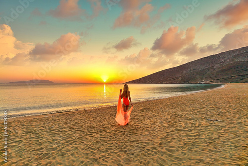 Young woman looking the sunrise from Agia Theodoti beach in Ios, Greece photo