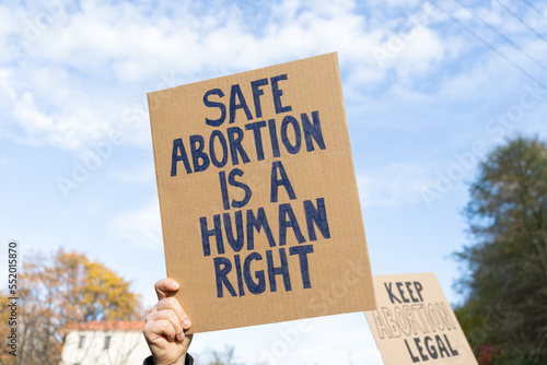 Protesters holding signs with slogans Safe abortion is a human right and Keep abortion legal. People with placards supporting abortion at protest rally demonstration. © Longfin Media