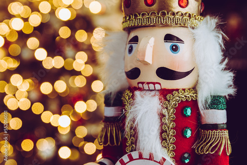 Christmas nutcracker wooden figure. Beautiful, festive toy soldier decoration, with Christmas tree lights bokeh in background. photo