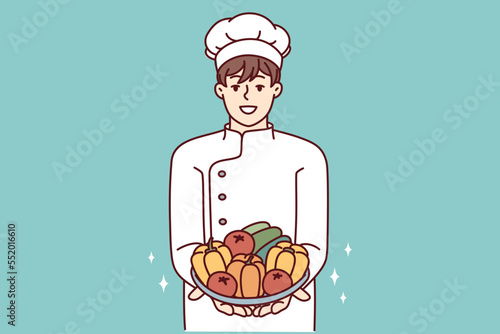Satisfied man in chef clothes holds plate with fresh vegetables in hands offering to make vegetable salad. Restaurant cook demonstrating ingredients for preparing vegetarian food. Flat vector design
