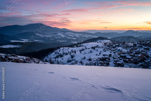 Beautiful sunrise view with snowy mountain slopes and small village among them in the frozen winter morning, the Rhodopi Mountains, Bulgaria © Jess_Ivanova