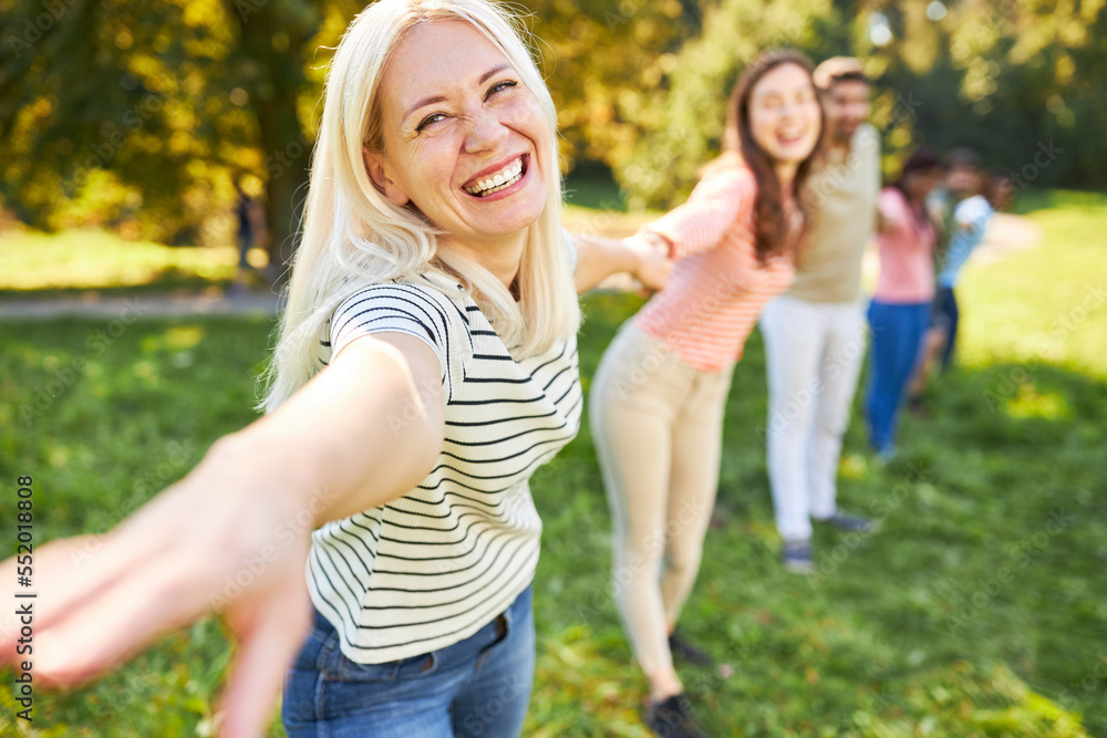 Fröhliche junge Frau und ihre Freunde Hand in Hand Fröhliche junge Frau und ihre Freunde Hand in Hand