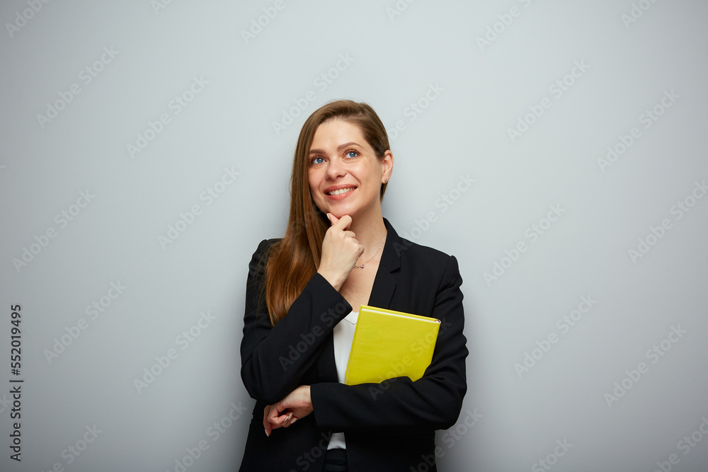 Thinking woman teacher holding yellow book. Isolated portrait with copy space. Thinking woman teacher holding yellow book. Isolated portrait with copy space.