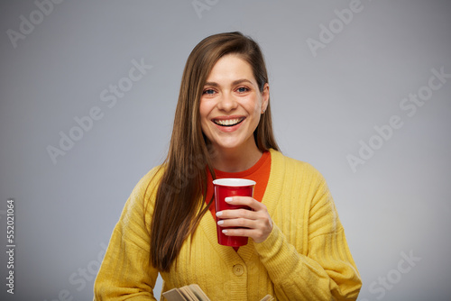 Smiling young woman holding drink or juice in glass. Isolated advertising portrait.