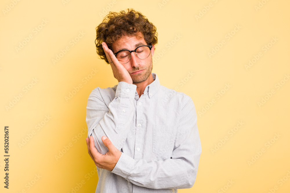 Young smart caucasian man on yellow background who is bored, fatigued and need a relax day. Young smart caucasian man on yellow background who is bored, fatigued and need a relax day.