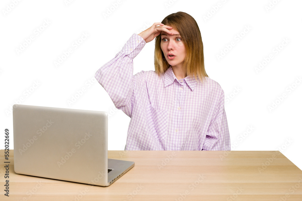 Young caucasian woman in a workplace working with a laptop isolated looking far away keeping hand on forehead. Young caucasian woman in a workplace working with a laptop isolated looking far away keeping hand on forehead.