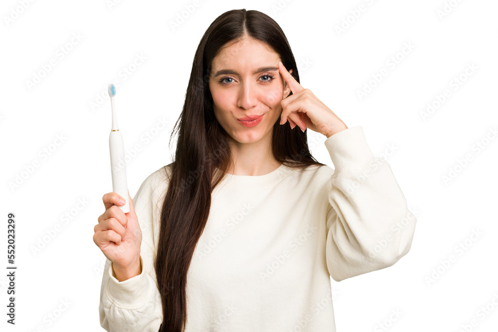 Young caucasian holding a brushing teeth isolated pointing temple with finger, thinking, focused on a task. Young caucasian holding a brushing teeth isolated pointing temple with finger, thinking, focused on a task.