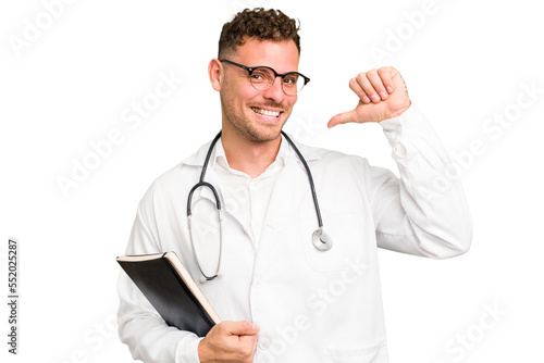 Young doctor caucasian man holding a book isolated feels proud and self confident, example to follow.