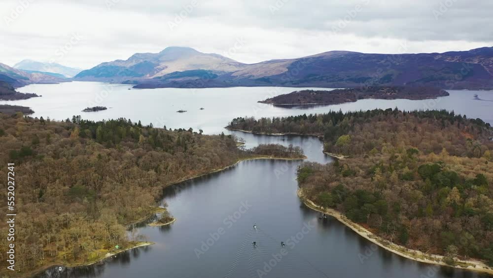 Aerial slowmo drone angle of boats travelling through the narrows on Loch Lomond, Scotland, with Luss and Ben Lomond in the background in early spring. Aerial slowmo drone angle of boats travelling through the narrows on Loch Lomond, Scotland, with Luss and Ben Lomond in the background in early spring.