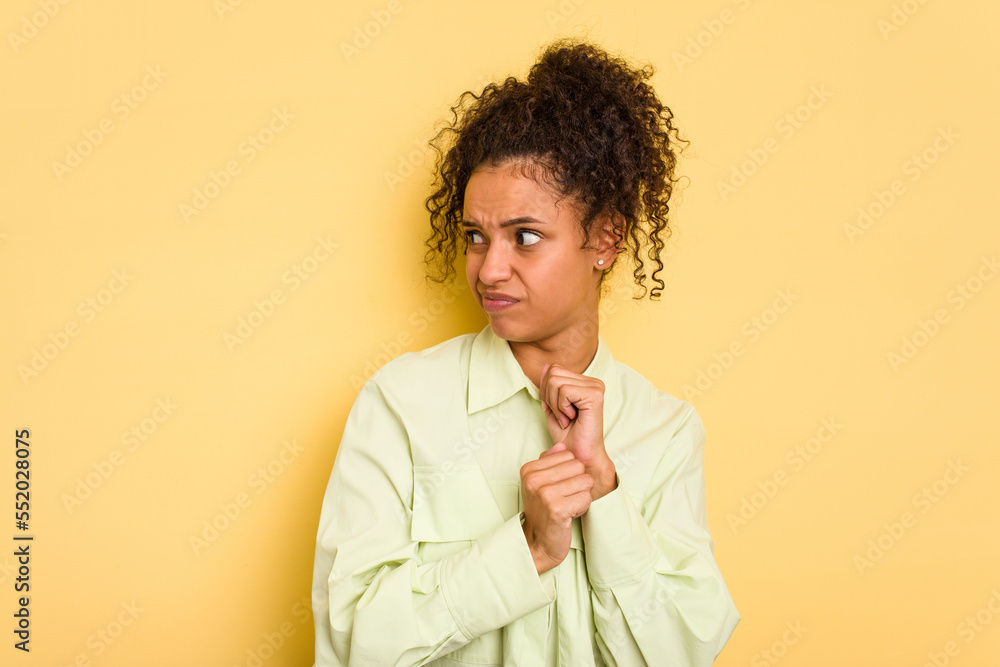 Young Brazilian curly hair cute woman isolated on yellow background confused, feels doubtful and unsure. Young Brazilian curly hair cute woman isolated on yellow background confused, feels doubtful and unsure.