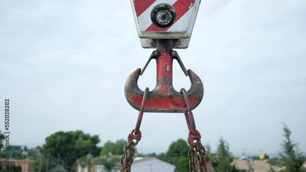 Strong steel chained crane pulley with weathered red paint lifting heavy equipment Strong steel chained crane pulley with weathered red paint lifting heavy equipment