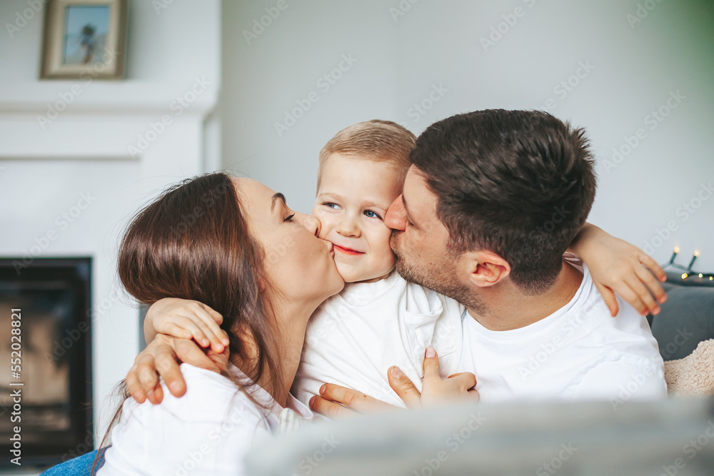 Young mother and father kissing their little son