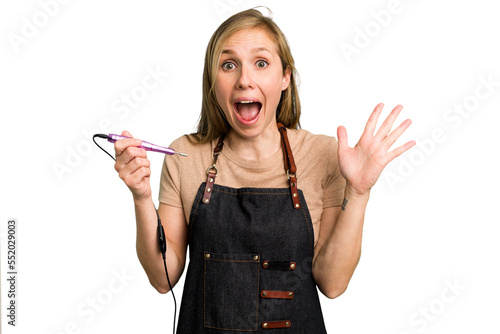 Fotografia Young caucasian manicurist woman holding an electric file drill isolated receiving a pleasant surprise, excited and raising hands