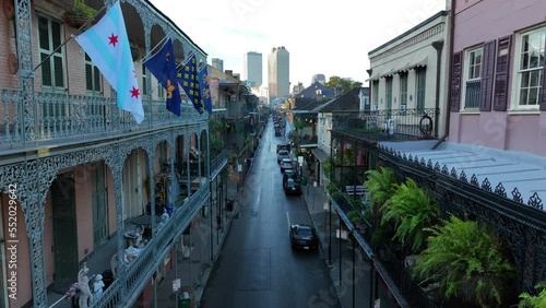 Galleries and flags adorn homes in French Quarter of New Orleans. Rising aerial reveals skyline and ferns. photo