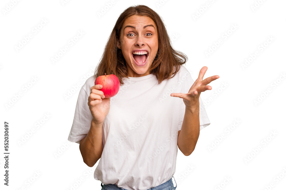 Young caucasian woman holding a red apple isolated receiving a pleasant surprise, excited and raising hands. Young caucasian woman holding a red apple isolated receiving a pleasant surprise, excited and raising hands.