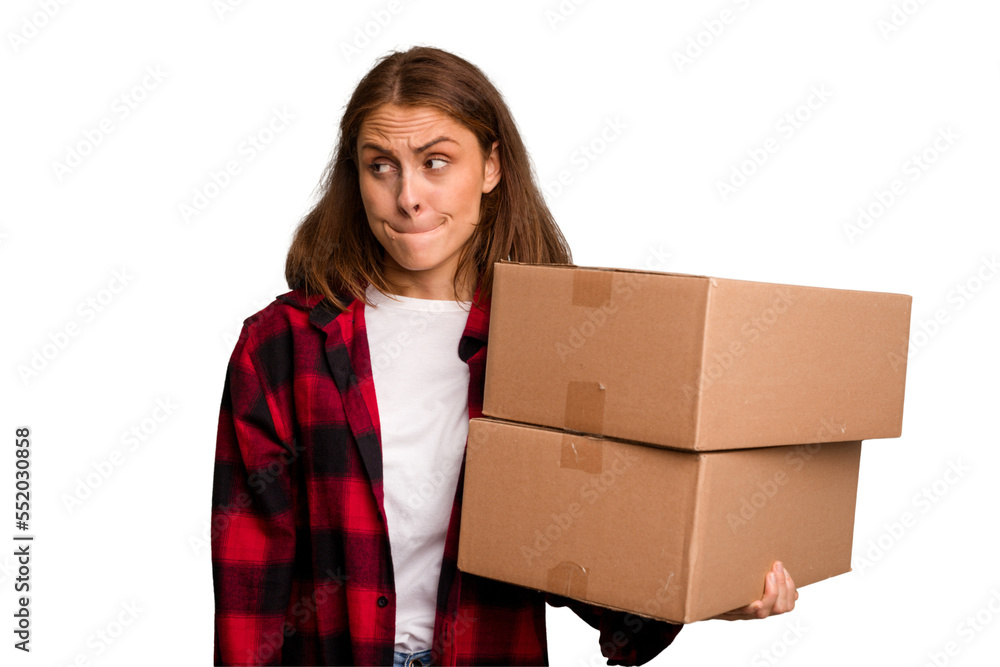 Young caucasian woman moving while picking up a box full of things isolated confused, feels doubtful and unsure. Young caucasian woman moving while picking up a box full of things isolated confused, feels doubtful and unsure.