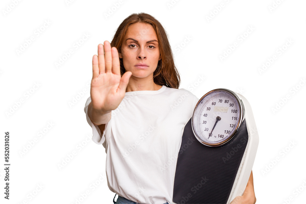 Young caucasian woman holding a scale and measure tape isolated standing with outstretched hand showing stop sign, preventing you. Young caucasian woman holding a scale and measure tape isolated standing with outstretched hand showing stop sign, preventing you.