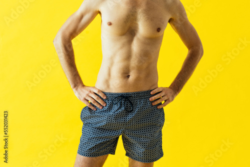 Handsome senior man posing in studio wearing beach trunks.