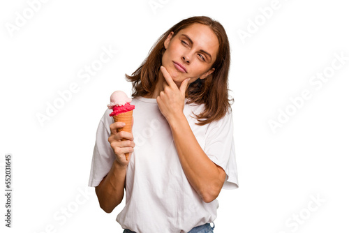 Young caucasian woman holding an ice cream isolated looking sideways with doubtful and skeptical expression.