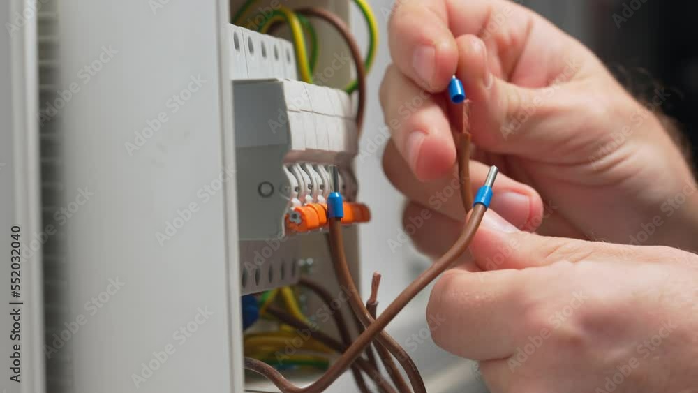 An electrician putting blue bushing ferrules on wires and clamping them. Close up of a mans hand