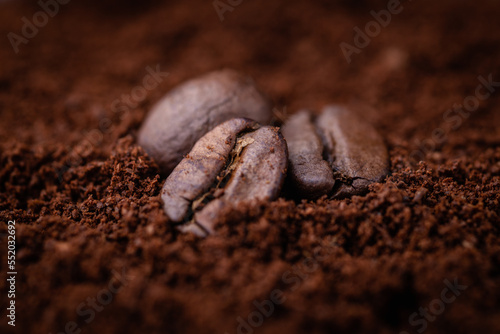 Three roasted coffee beans lie on a bed of ground coffee. Macro photo close up. Cafe.