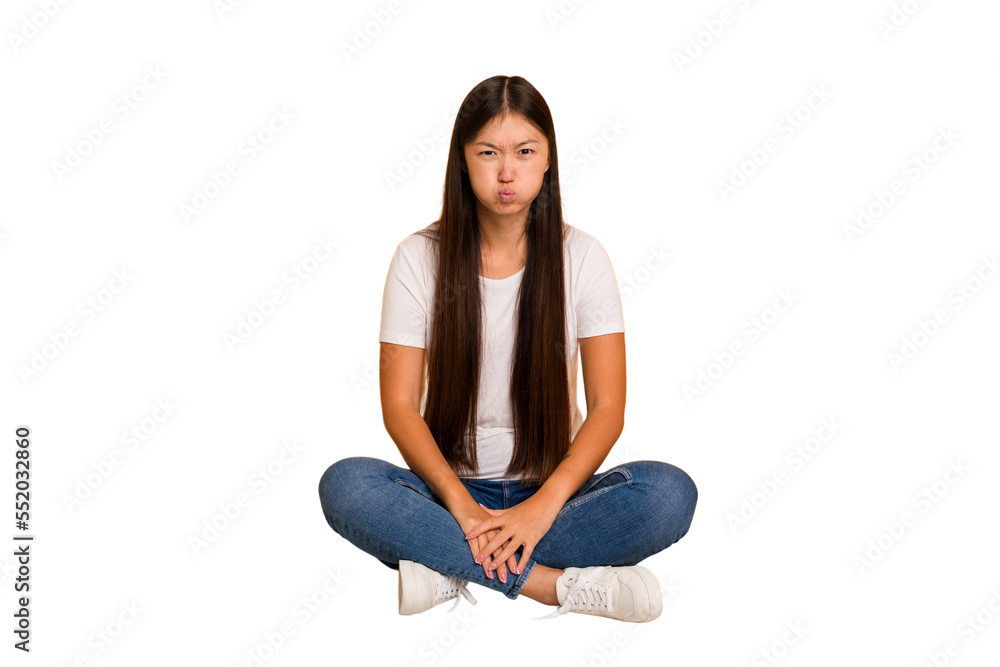 Young asian woman sitting on the floor cutout isolated blows cheeks, has tired expression. Facial expression concept. Young asian woman sitting on the floor cutout isolated blows cheeks, has tired expression. Facial expression concept.