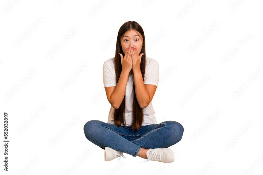 Young asian woman sitting on the floor cutout isolated shocked, covering mouth with hands, anxious to discover something new. Young asian woman sitting on the floor cutout isolated shocked, covering mouth with hands, anxious to discover something new.