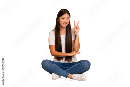 Young asian woman sitting on the floor cutout isolated showing number two with fingers. © Asier
