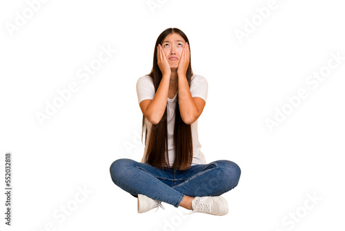 Young asian woman sitting on the floor cutout isolated whining and crying disconsolately. photo