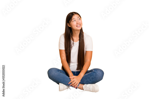Young asian woman sitting on the floor cutout isolated relaxed and happy laughing, neck stretched showing teeth.