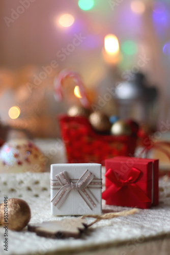 Various colorful Christmas decorations, soft blanket, cup of tea, sweet snacks and lit candles on the table. Cozy Christmas atmosphere at home. Selective focus.