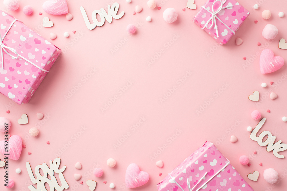 St Valentine's Day concept. Top overhead view photo of present boxes heart shaped candles inscriptions love sprinkles and soft pompons on isolated pastel pink background with blank space in the middle