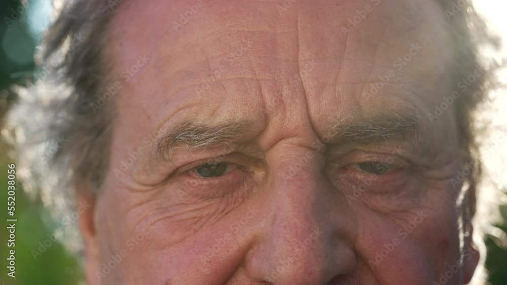 One senior man opening eyes to camera outside in nature. A mature older male person awakening from meditation One senior man opening eyes to camera outside in nature. A mature older male person awakening from meditation