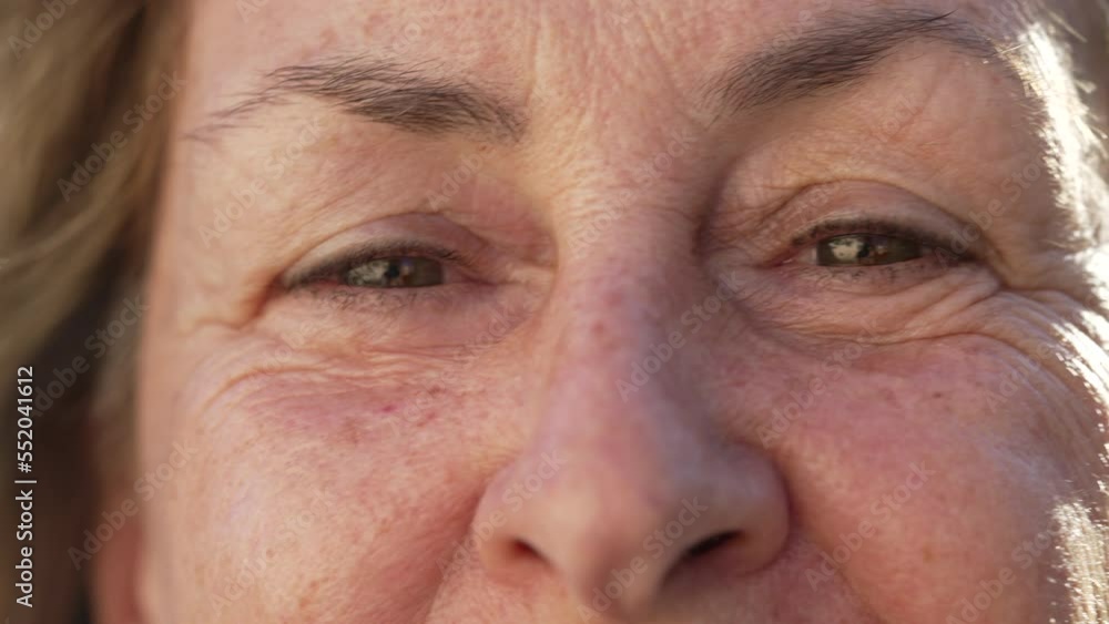 Joyful senior woman macro eyes close up looking at camera. Expressive aged older female person in 70s Joyful senior woman macro eyes close up looking at camera. Expressive aged older female person in 70s