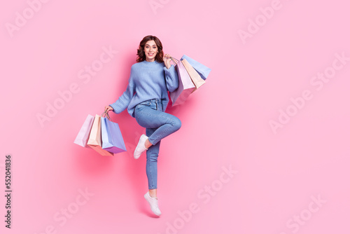 Full body photo of pretty excited lady hold boutique bags jumping empty space isolated on pink color background