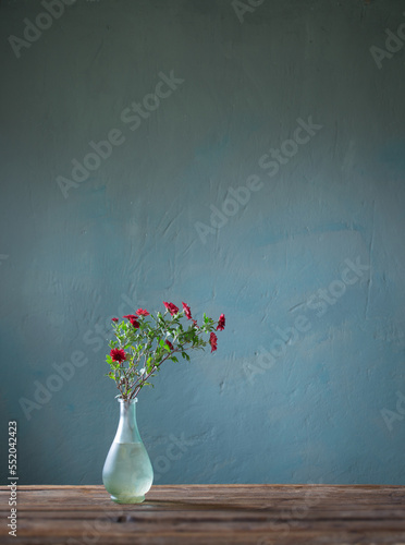 red chrysanthemums in glass vase on dark background