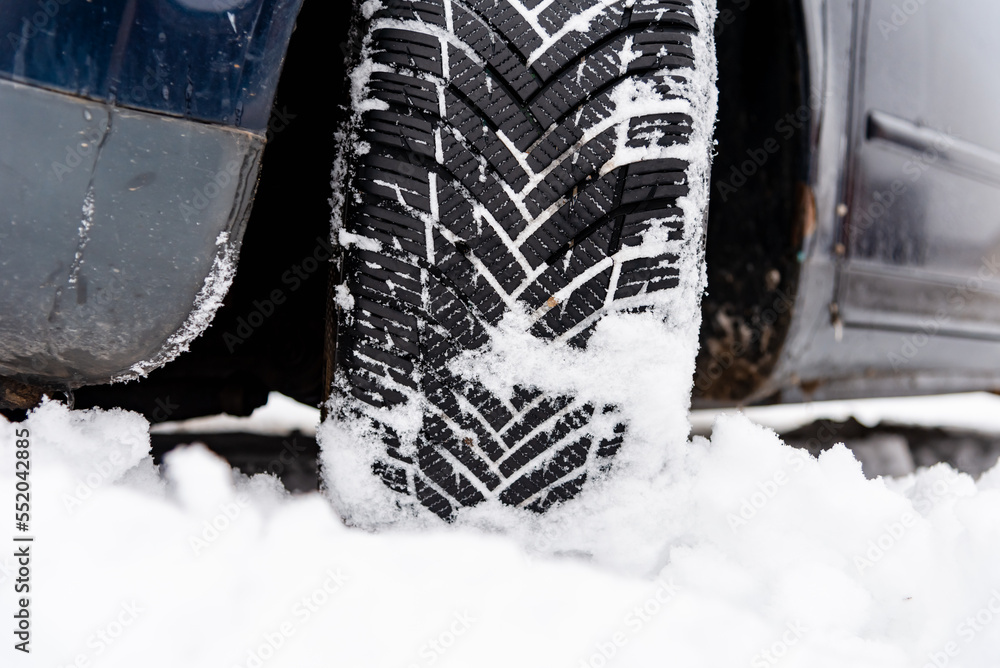 Car tires on winter road covered with snow.Vehicle on snowy alley.Winter tire.Detail of car tires in winter on the road covered with snow.
