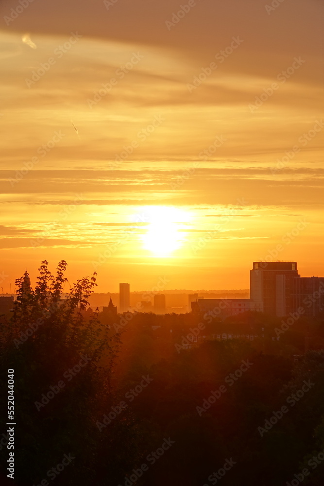 Vivid orange sky sunrise over central London viewed from Hampstead Heath, UK