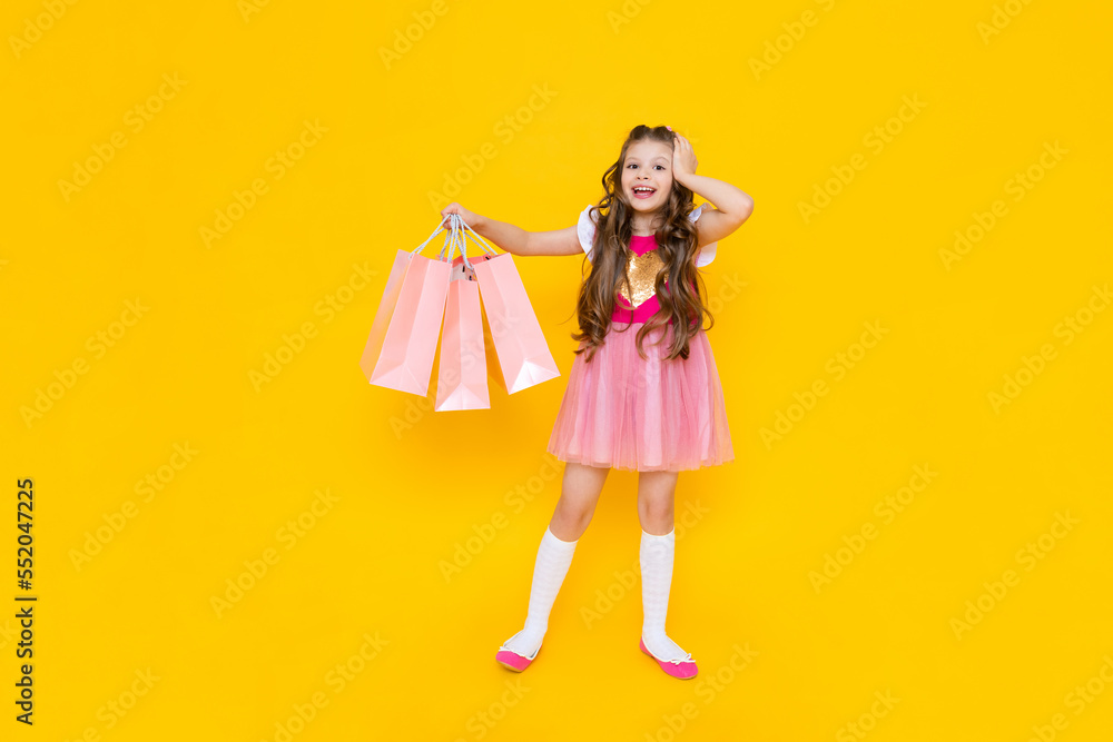A girl in a pink dress is holding large bags of new things in her hands. New purchases for the summer, shopping at the mall.