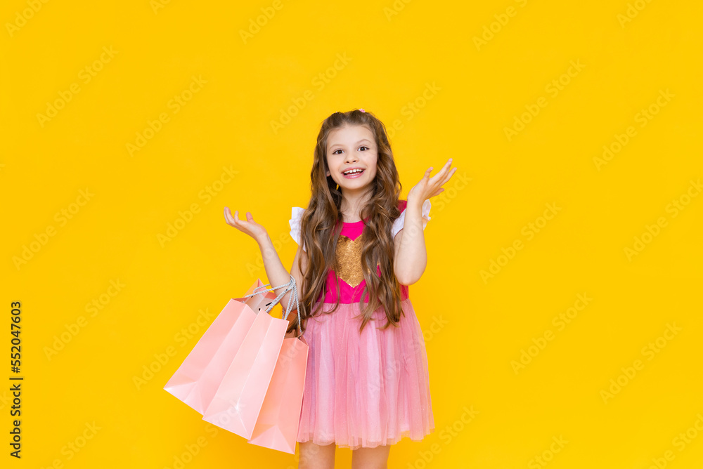 A beautiful little girl in a pink dress is happy to make new purchases from the store, shopping in the store for spring, new children's cooks for the promotion.